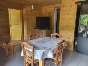 jadalnia ze stołem, krzesłami i telewizorem w obiekcie Appartement cosy face aux Aravis w mieście Le Grand-Bornand
