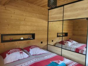 dwa łóżka w pokoju z drewnianymi ścianami w obiekcie Appartement cosy face aux Aravis w mieście Le Grand-Bornand