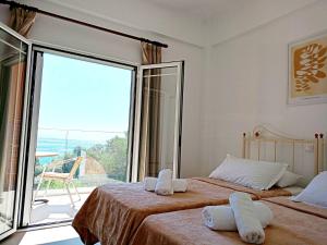 a bedroom with two beds and a large window at Rena Studios in Paleokastritsa