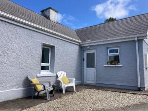 a blue house with two chairs and a window at Annie's Cottage On The Corner in Donegal
