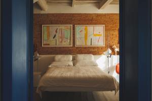 a bedroom with a bed with three paintings on the wall at Residenza dell'Orto - Residenze Tonnina Group in Guardistallo