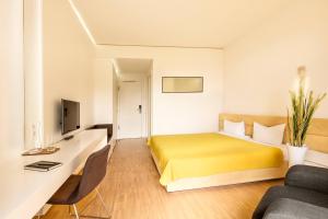 ドッセンハイムにあるミドリ ザ グリーン ゲストハウスの黄色のベッドとソファが備わるホテルルームです。