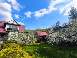a garden with flowering trees and a house at Apartamenty & Domek Gawędówka in Krościenko