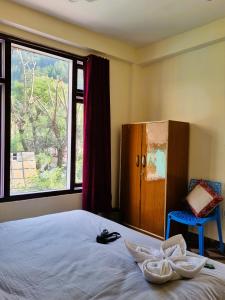 a bedroom with a bed and a large window at Parvati Hill View in Kasol
