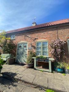 a brick house with a bench and a blue door at Beech Farm cottages in Tetney