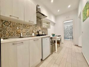 a kitchen with white cabinets and a table in it at lungomare rooms in Castellammare di Stabia
