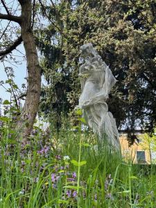 a statue in a field of flowers in front of a tree at Relais Villa Alma in Castion Veronese