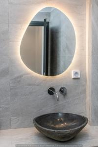 a sink in a bathroom with a round mirror at Rockaine Suites Eclipse in Tinos