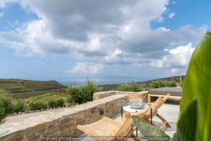 a patio with a table and chairs on a stone wall at Rockaine Suites Eclipse in Tinos +11 photos