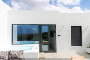 a white house with a swimming pool in it at Rockaine Suites Eclipse in Tinos