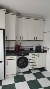 a kitchen with white cabinets and a washing machine at Casa Angela in Santoña