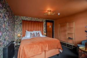 a bedroom with a large bed with a orange bedspread at Boutique Pension Code Rosé in Noordwijk