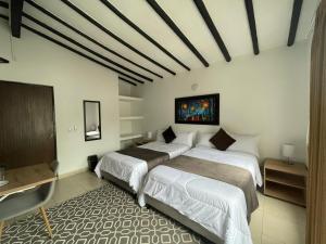 a bedroom with two beds and a tv in it at Aguacatala Hotel Boutique in Medellín
