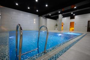 a large swimming pool with blue water in a building at Noble Samarkand in Samarkand