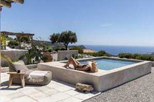 a woman in a bikini laying next to a swimming pool at Palazzo Greco Villas in Agia Galini