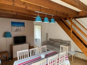 ein Wohnzimmer mit Tisch und Stühlen und einer Couch in der Unterkunft Patrimoine et immobilier Villas du Lac in Soustons