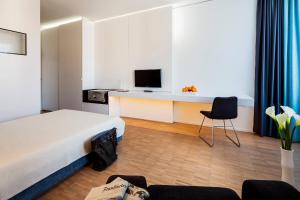 Cette chambre comprend un lit et un bureau avec une télévision. dans l'établissement Midori - The Green Guesthouse, à Dossenheim