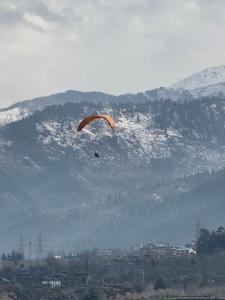 a person flying a kite in front of a mountain at Zankhrpas A Himalayan Home - Manali in Manāli