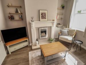 a living room with a television and a fireplace at Middle Cottage in Louth