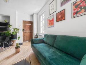 a living room with a green couch and a table at Nid douillet cosy au cœur d'Angers, idéal à deux in Angers