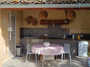 a kitchen with a table with a pink table cloth at chambre d hotes la dragonne in Maubec