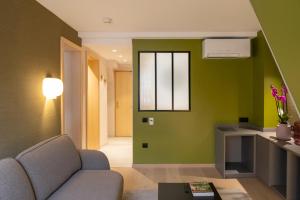 a living room with a couch and a green wall at Logis Hôtel Restaurant Au Cerf d'Or in Strasbourg
