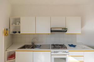 une cuisine avec des armoires blanches et un four à plaques de cuisson dans l'établissement Casa Vista Darsena - HelloElba, à Portoferraio 9 autres photos