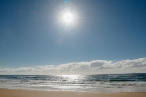 a beach with the sun shining over the ocean at Na Villa dos Algodões in Marau