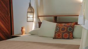 a bedroom with a bed with pillows and a lamp at Na Villa dos Algodões in Marau