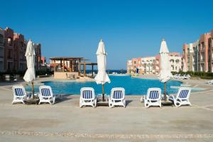 a group of chairs and umbrellas next to a pool at Oyster bay resort studio in Marsa Alam