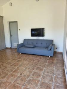 a living room with a blue couch and a flat screen tv at Jolie maison avec jardin et pergola in Hastingues
