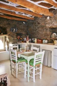 a kitchen with a white table and chairs at Παραδοσιακός πέτρινος ξενώνας σε φάρμα in Fállika +32 photos