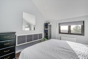 a white bedroom with a bed and a mirror at City Line Apartment 2 in Newtownabbey
