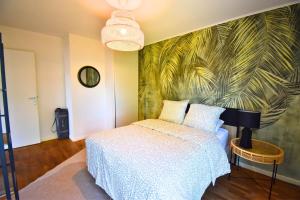 a bedroom with a bed and a palm mural at Le Bicolore Parisien in Aubervilliers