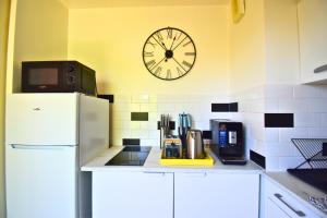 a kitchen with a refrigerator and a clock on the wall at Le Bicolore Parisien in Aubervilliers +7 photos