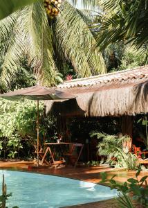 an umbrella and a table and a swimming pool at Na Villa dos Algodões in Marau