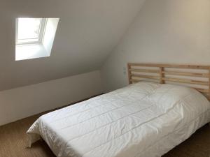a white bed in a bedroom with a window at La Maison de Marin in Surtainville