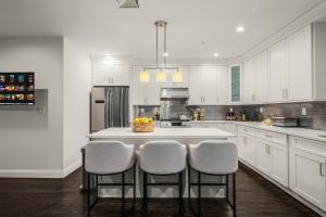a kitchen with white cabinets and a island with bar stools at Stylish 3BR Designer Home in Harlem! in New York +32 photos