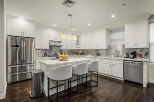 a kitchen with white cabinets and a island with bar stools at Stylish 3BR Designer Home in Harlem! in New York