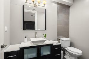 a bathroom with a sink and a toilet and a mirror at Stylish 3BR Designer Home in Harlem! in New York