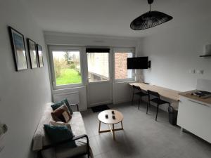 a living room with a couch and a table and a desk at La petite pause Béthunoise in Béthune