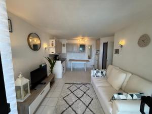 Una sala de estar con un sofá blanco y un televisor. en a 2 minutes de la plage vue mer et piscine, en Cannes