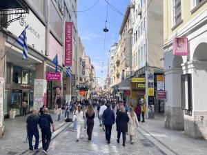a group of people walking down a busy city street at K8 Syntagma in Athens