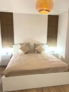 una camera da letto con un letto grande con un lampadario di Comme à la maison, en Normandie a Gruchet-le-Valasse
