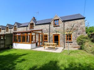 une maison en pierre avec une table de pique-nique dans la cour dans l'établissement Cove Cottage, à Llandysul