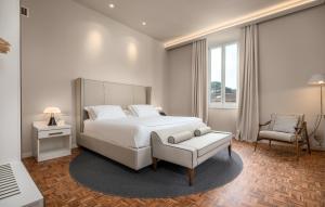 a white bedroom with a bed and a chair at Palazzo BelVedere in Montecatini Terme