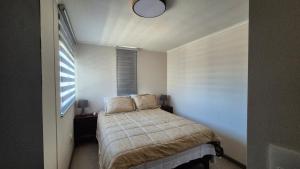 a small bedroom with a bed and a window at Departamento Corporativo IV Las Rastras ' San Miguel - RENTCOVAC - Factura Inmediata in Talca