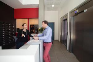 a man and a woman shaking hands at a counter at Résidence Odalys Paris Rueil in Rueil-Malmaison