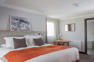 a bedroom with a large bed with an orange blanket at Bosville Hotel in Portree