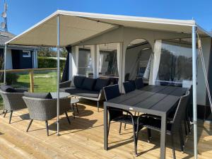 a gazebo with a table and chairs on a deck at Løkken Klit GLAMPING in Løkken
